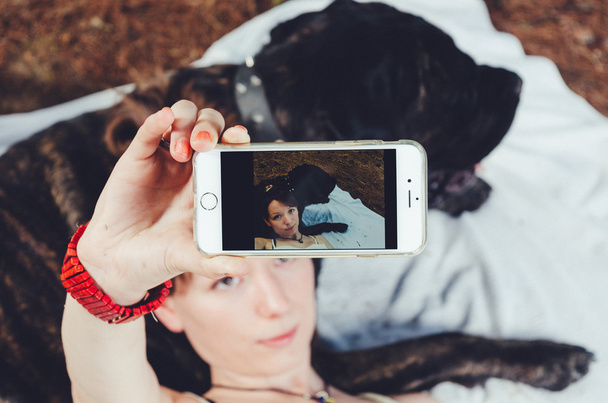 Girl on picnic taking a selfie with her big dog.  - Photo, image