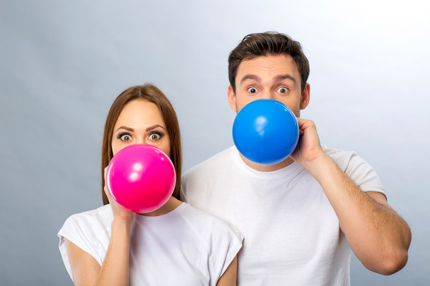 Cheerful young couple blowing balloons - Foto, Imagem