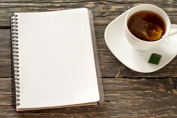 open notebook with blank pages with cup of black tea - Fotó, kép