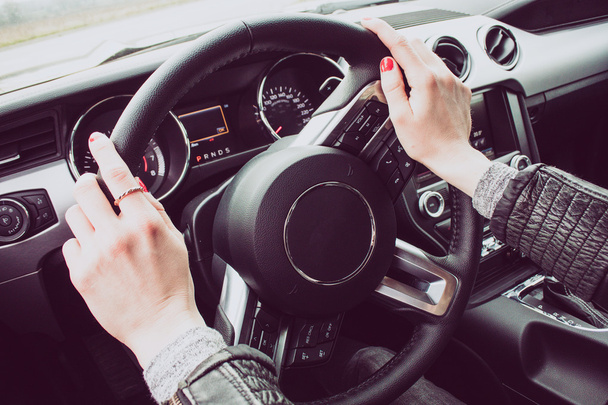 Kadın sürücü Eller direksiyonda görüntüsünü kapatın. Kırmızı boyalı tırnaklar. - Fotoğraf, Görsel
