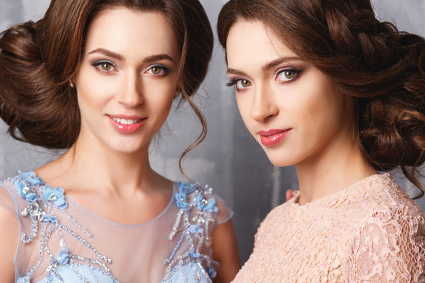 Close-up portrait of beautiful twins young women in luxury dresses, pastel colors. Beauty fashion portrait - Fotoğraf, Görsel