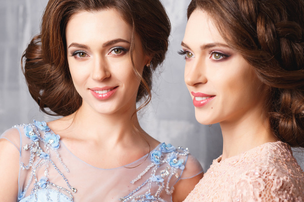Close-up portrait of beautiful twins young women in luxury dresses, pastel colors. Beauty fashion portrait - Foto, imagen