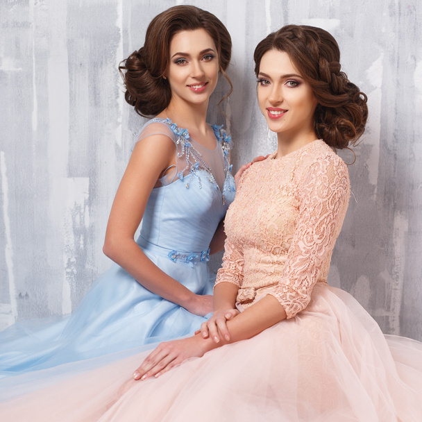 Dos hermosas gemelas mujeres jóvenes en vestidos de lujo, colores pastel. Retrato de moda de belleza
 - Foto, Imagen