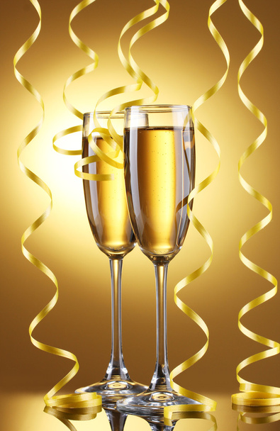 Glasses of champagne and streamer on yellow background - Foto, Imagem