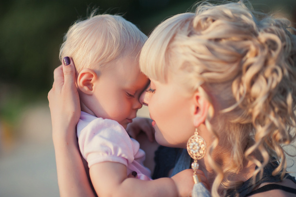 Beautiful happy mother hugging baby girl with love outdoors summer background - Photo, Image