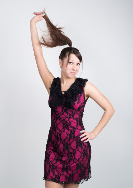 Beautiful young leggy brunette in a little red dress pulls his hair - Фото, зображення