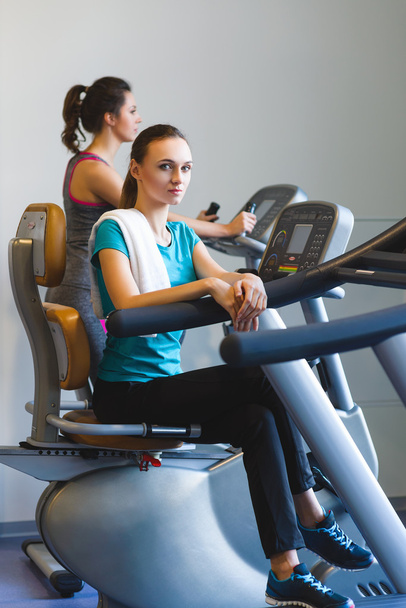 Mädchen ruht sich im Fitnessstudio auf einem Crosstrainer aus - Foto, Bild