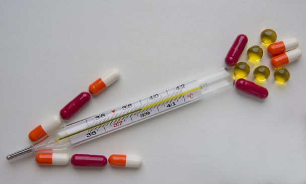 Termometr i tabletki wielobarwne na białym tle - Zdjęcie, obraz