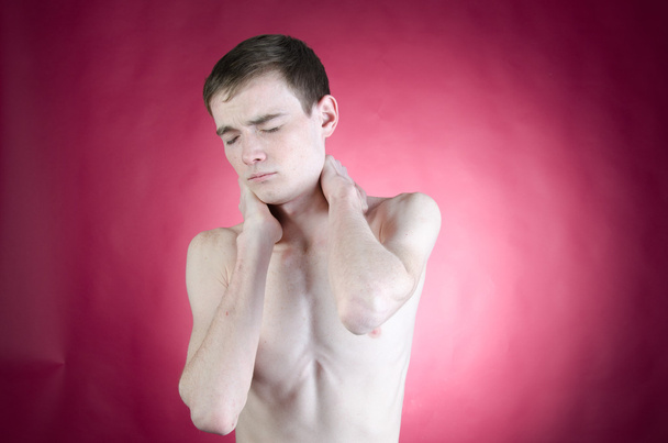 un joven sosteniendo el cuello con dolor
 - Foto, imagen