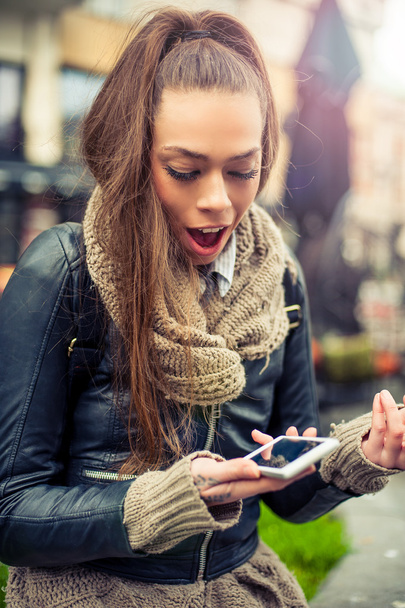 Hymyilevä nuori nainen käyttää mobiili kadulla
 - Valokuva, kuva