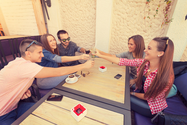 Jóvenes amigos riendo y brindando en la cafetería
 - Foto, imagen