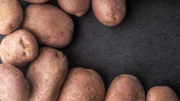 Raw potatoes on the dark stone table horizontal - Fotografie, Obrázek