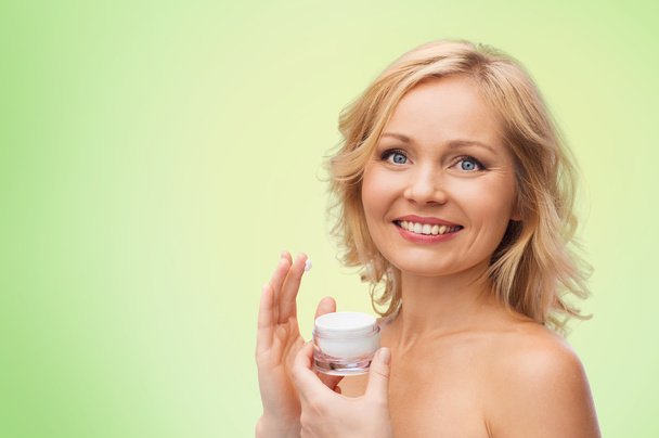 happy woman applying cream to her face - Zdjęcie, obraz