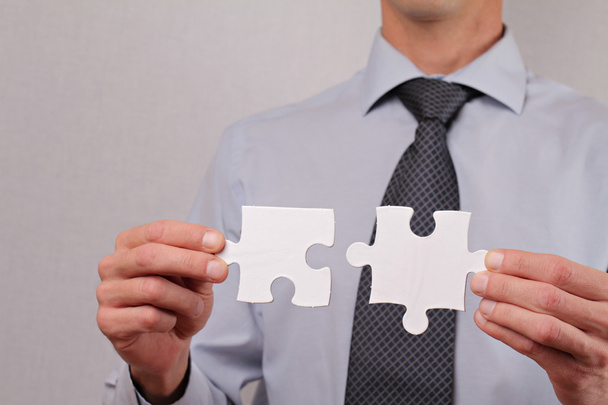 Business solutions, partnership concept. Businessman holding two pieces of a blank puzzle - Φωτογραφία, εικόνα