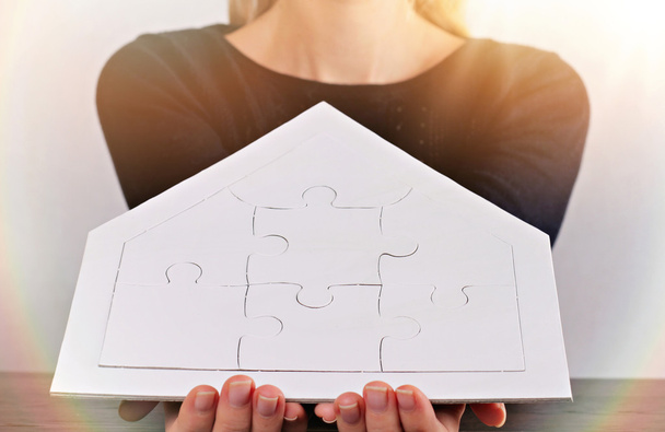 Szczęśliwe wartości rodzinne, ubezpieczenie domu, koncepcja inwestycji w nieruchomości. Kobieta trzyma dom kształt puste puzzle. Kopiuj przestrzeń obrazu - Zdjęcie, obraz