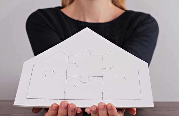 Szczęśliwe wartości rodzinne, ubezpieczenie domu, koncepcja inwestycji w nieruchomości. Kobieta trzyma dom kształt puste puzzle. Kopiuj przestrzeń obrazu - Zdjęcie, obraz