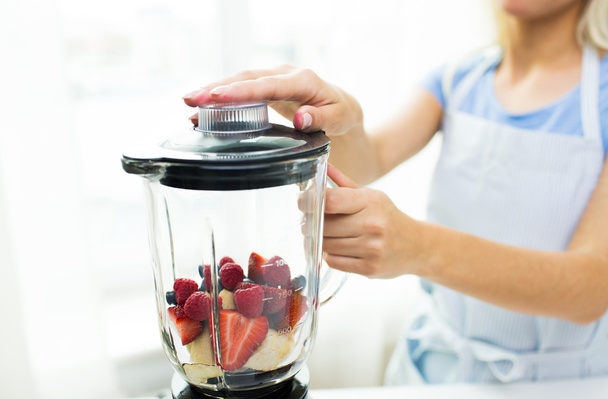 close up of woman with blender making fruit shake - Foto, Bild