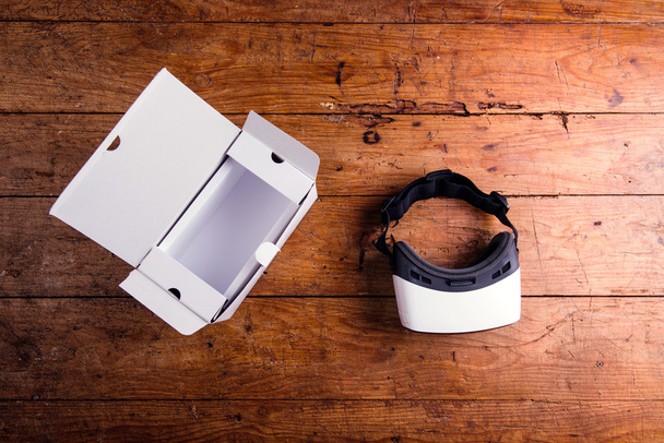 Virtual reality goggles with paper box on wooden table - Valokuva, kuva