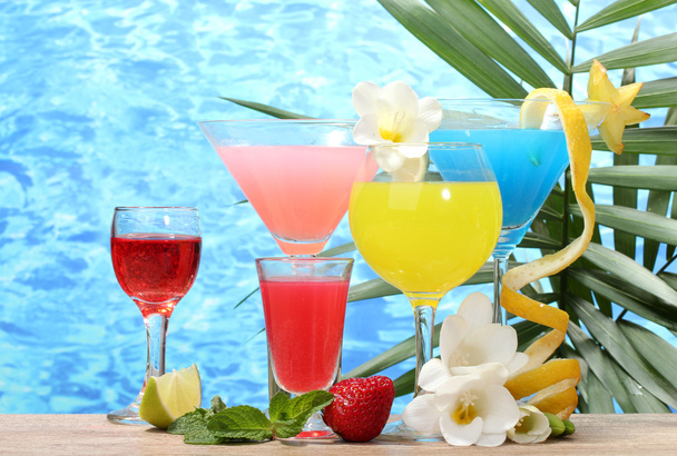 Exotic cocktails and flowers on table on blue sea background - Foto, afbeelding