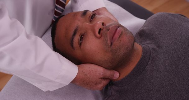 Chiropraticien vérifiant blessure au cou d'un patient africain de sexe masculin
 - Photo, image