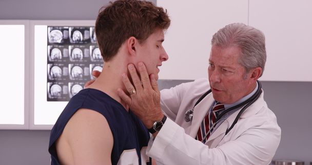 Portrait of mid-aged doctor check sports athlete neck injury - Photo, Image