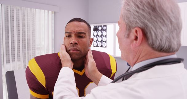 jogador de futebol universitário tendo médico sênior rever seu concussi
 - Foto, Imagem