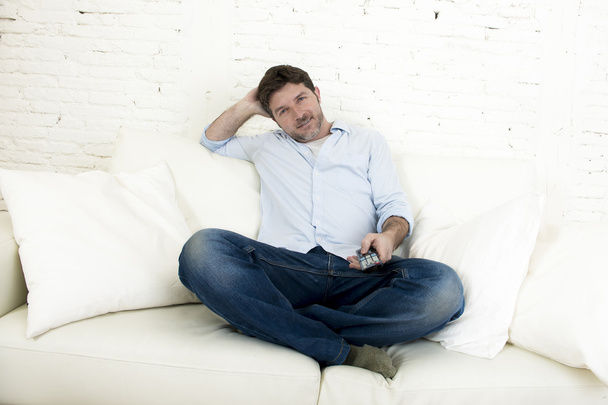 giovane uomo felice guardando la tv seduto a casa divano soggiorno cercando rilassato godendo la televisione
 - Foto, immagini