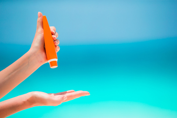 Suncream ボトル青背景海で女性の手 - 写真・画像