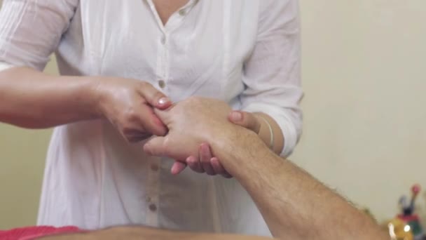 El primer plano de las manos masajistas hacen el masaje de los dedos de la mano al hombre adulto. Asistencia sanitaria
 - Imágenes, Vídeo