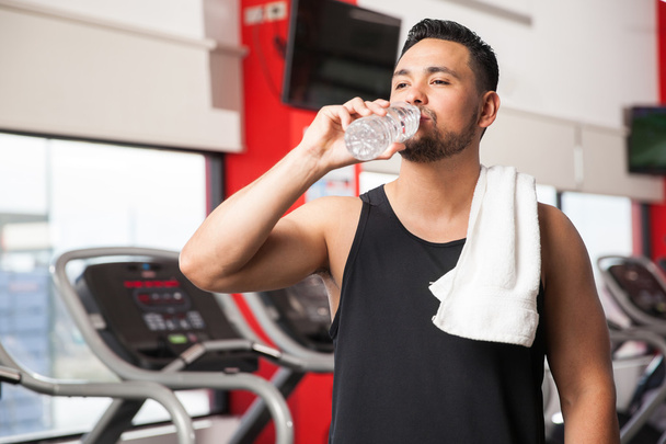 man drinkwater in een sportschool - Foto, afbeelding