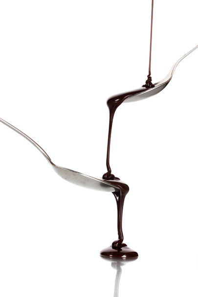 Chocolate poured into a spoon and from it to another spoon isolated on white - Foto, imagen