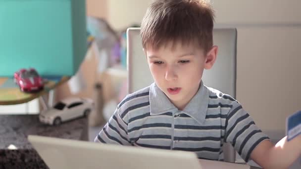 Netter kleiner Junge benutzt Laptop und Kreditkarte - Filmmaterial, Video