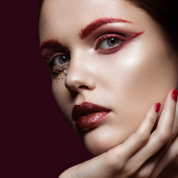 Beautiful girl with a bright red fashion makeup and crystals on the face. Close-up portrait. - Foto, Imagen