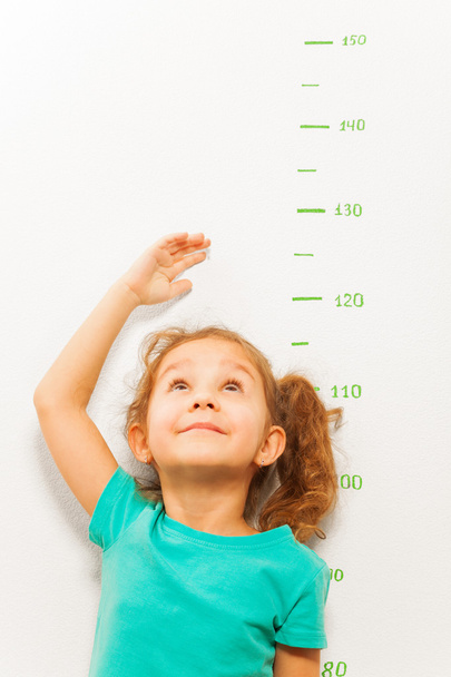 Girl measure height with hand looking up - Фото, изображение