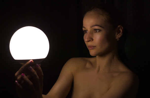 beautiful young leggy blond gir in the dark, holding in front of a lamp, expresses different emotions - 写真・画像
