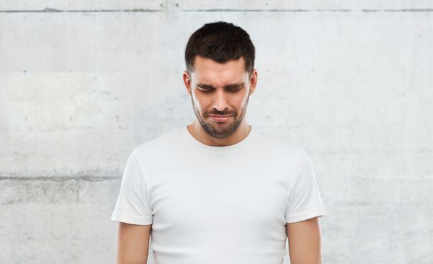 unhappy young man over gray wall background - Foto, afbeelding