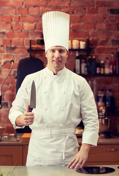 happy male chef cook in kitchen with knife - Фото, зображення