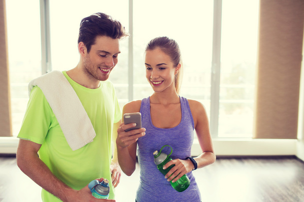 happy woman and trainer showing smartphone in gym - Photo, Image