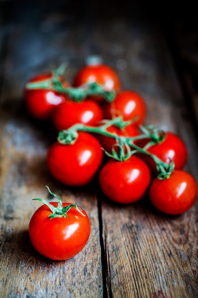 Tomatoes on the vine on rustic wooden background - Foto, afbeelding