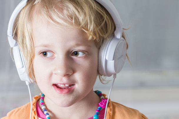 Little girl listening to music on headphones. Portrait. - Фото, изображение