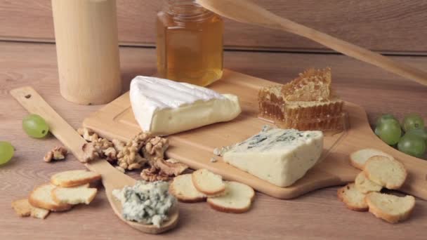 Různé druhy sýrů, medu a hroznů na dřevěné backgrouond - Záběry, video