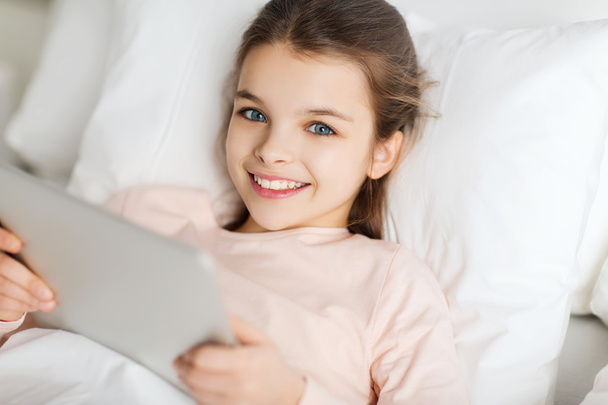 happy girl lying in bed with tablet pc at home - Zdjęcie, obraz