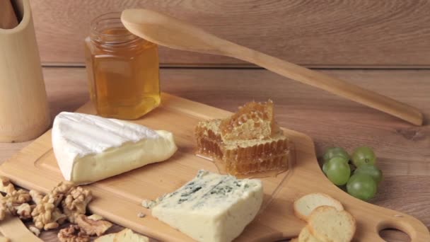 Different type of cheese, honey and grape on wooden backgrouond - Footage, Video