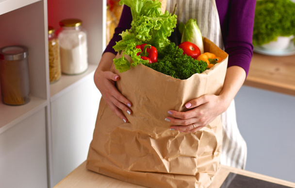 Assorted fruits and vegetables in brown grocery bag holding a young girl - Photo, Image