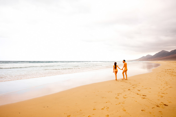 Naakte paar wandelen op het strand - Foto, afbeelding