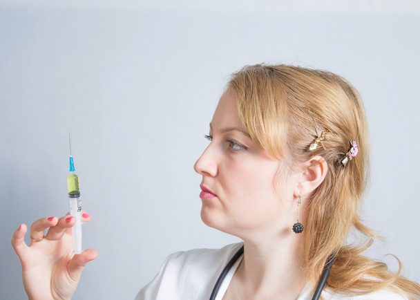 Doctor with stethoscope at the neck holding syringe for injection - Photo, Image