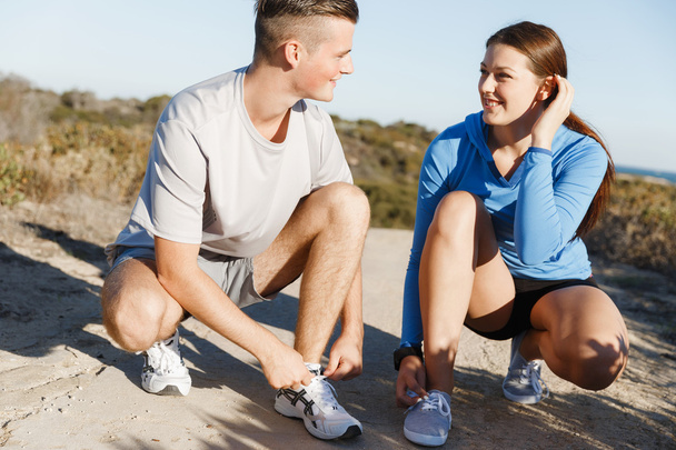 Couple of runners lace their shoes and prepare to jogging - Фото, изображение