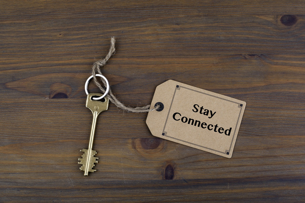Sleutel en een opmerking op een houten tafel met tekst - Stay Connected - Foto, afbeelding