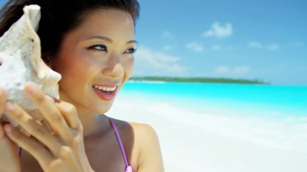Menina chinesa segurando concha na praia tropical
 - Filmagem, Vídeo