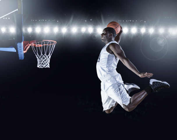 Παίκτης μπάσκετ σκοράροντας ένα slam dunk καλάθι. - Φωτογραφία, εικόνα